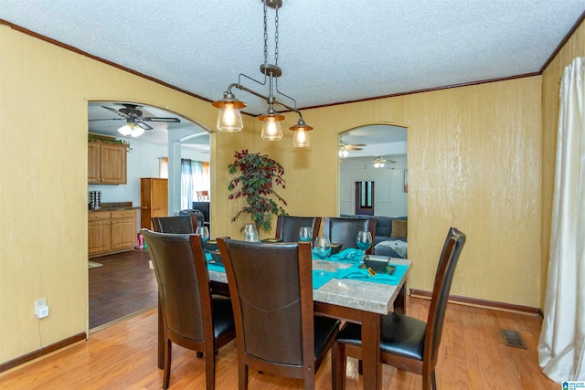 dining space featuring light hardwood / wood-style flooring, a textured ceiling, and crown molding