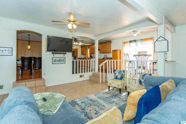 living room featuring wooden walls, light tile patterned floors, and vaulted ceiling with beams