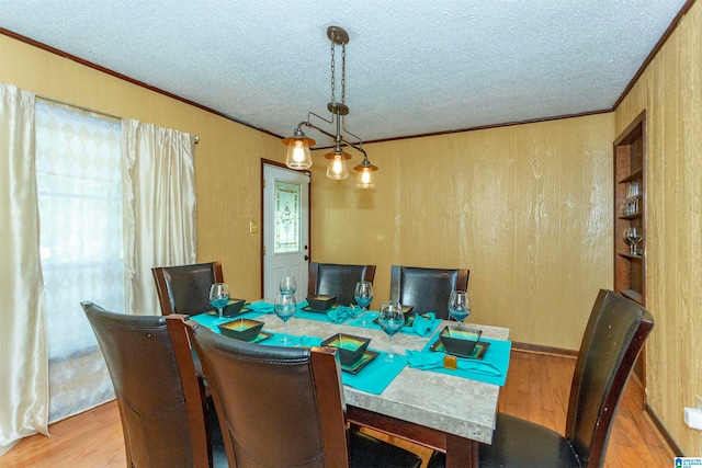 dining area featuring a textured ceiling, crown molding, and light hardwood / wood-style flooring