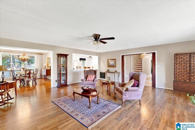 living room with hardwood / wood-style floors, a textured ceiling, and ceiling fan with notable chandelier