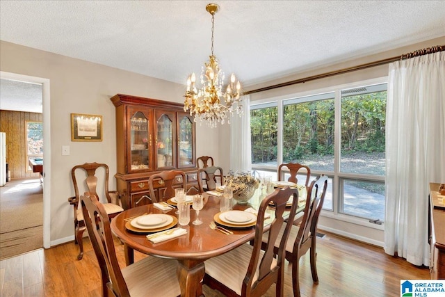 dining area with an inviting chandelier, a textured ceiling, and light hardwood / wood-style floors