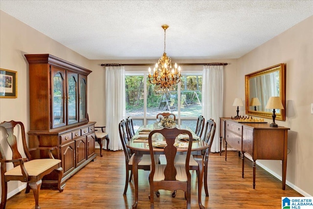 dining area with light hardwood / wood-style floors, a textured ceiling, and a chandelier