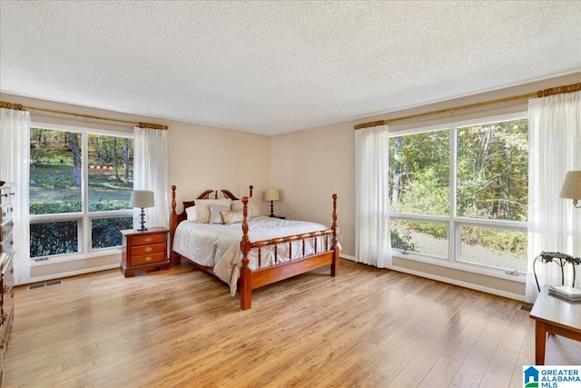 bedroom with a textured ceiling and light wood-type flooring