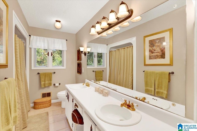 bathroom with vanity, toilet, a textured ceiling, and tile patterned flooring