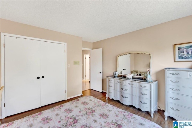 bedroom with a closet, a textured ceiling, and hardwood / wood-style flooring