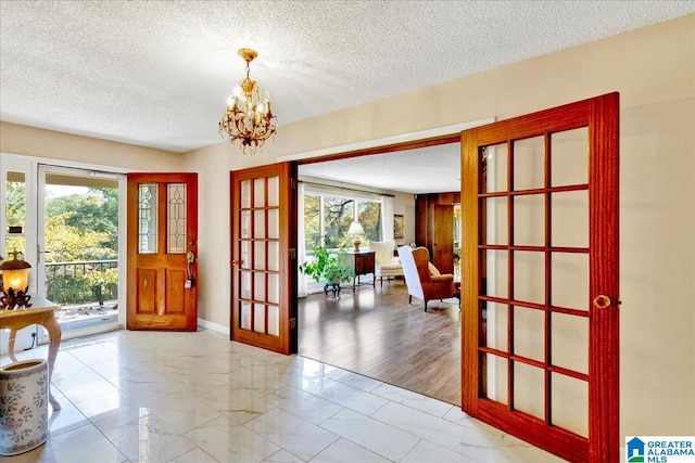 doorway featuring hardwood / wood-style floors, a notable chandelier, a textured ceiling, and french doors