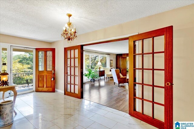 1215 Red Valley Rd, Remlap, AL 35133 - entryway featuring french doors, marble look tiles, a chandelier, a textured ceiling, and baseboards