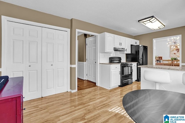 kitchen with black appliances, light wood-type flooring, white cabinetry, decorative backsplash, and an inviting chandelier