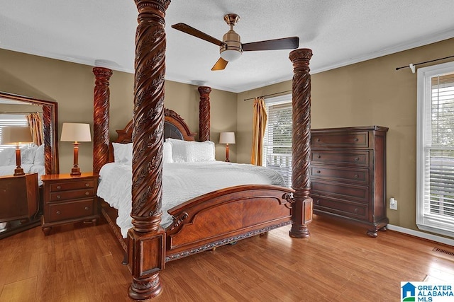 bedroom with multiple windows, hardwood / wood-style floors, crown molding, and ceiling fan