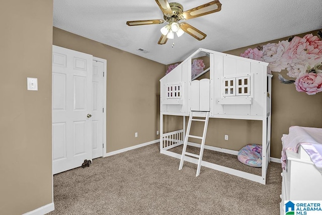 carpeted bedroom with ceiling fan and a textured ceiling