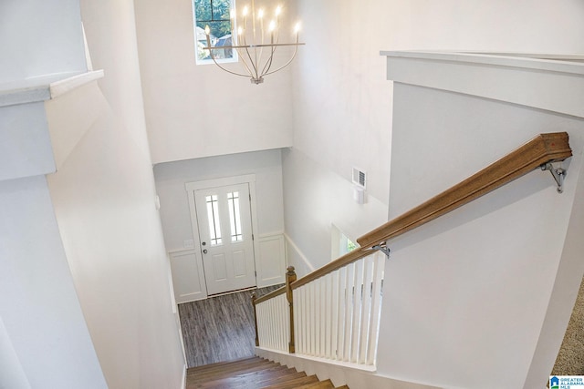 stairway with a notable chandelier and wood-type flooring