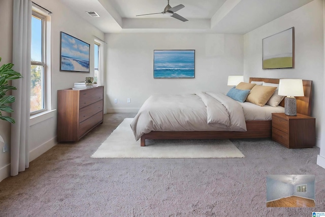 carpeted bedroom featuring a tray ceiling and ceiling fan