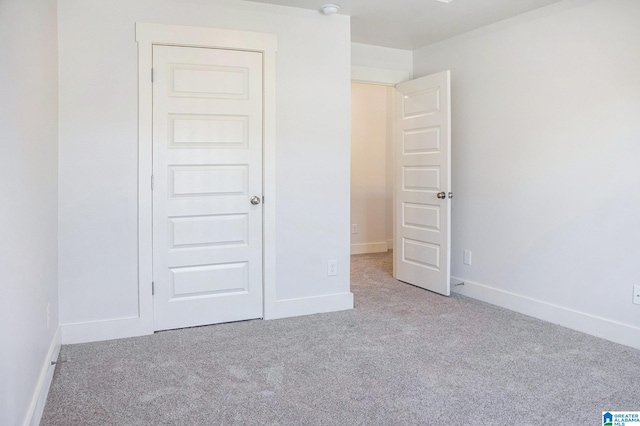 unfurnished bedroom with light carpet and a closet