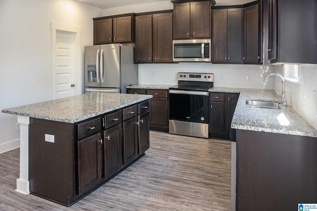 kitchen featuring a kitchen island, dark brown cabinets, stainless steel appliances, sink, and light hardwood / wood-style floors