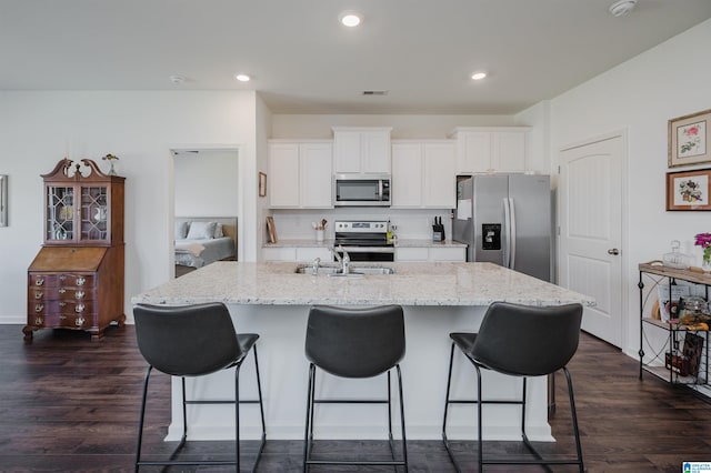 kitchen with appliances with stainless steel finishes, white cabinets, a kitchen island with sink, and dark wood-type flooring