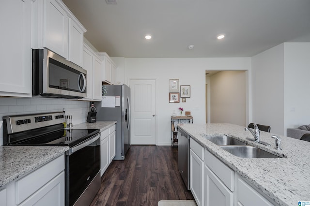 kitchen with appliances with stainless steel finishes, white cabinetry, light stone countertops, dark wood-type flooring, and sink