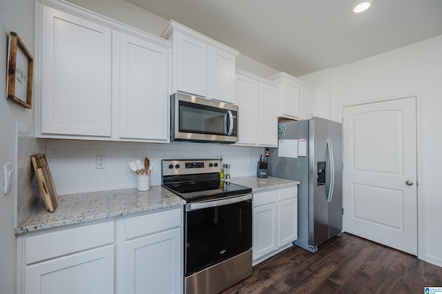 kitchen with light stone counters, appliances with stainless steel finishes, dark hardwood / wood-style flooring, and white cabinets