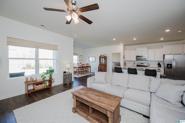 living room featuring dark wood-type flooring and ceiling fan