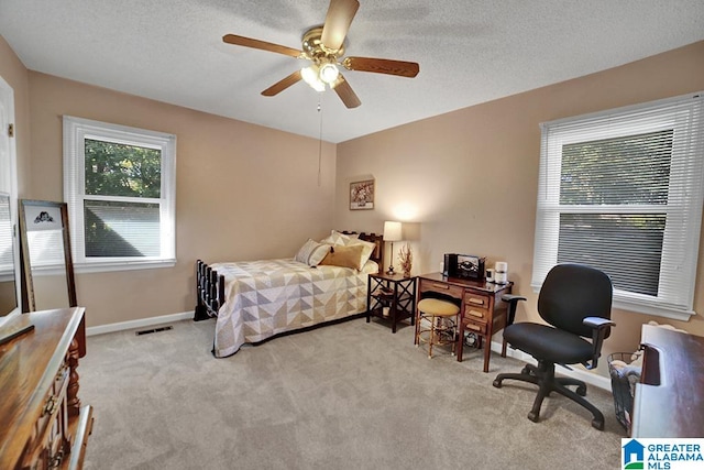 bedroom featuring a textured ceiling, light colored carpet, and ceiling fan