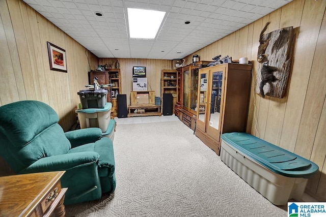 sitting room with a paneled ceiling, carpet flooring, and wooden walls