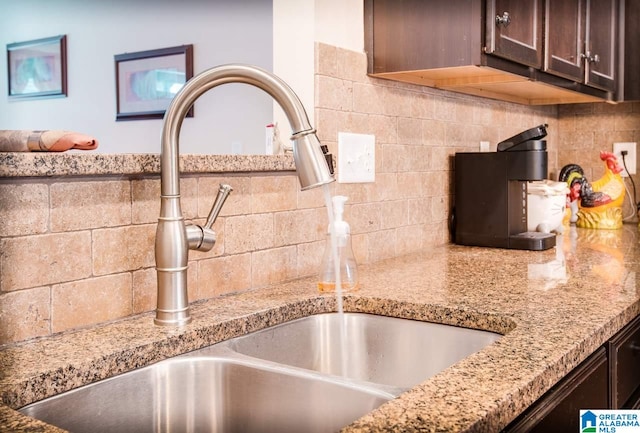 details with sink, light stone counters, dark brown cabinets, and backsplash