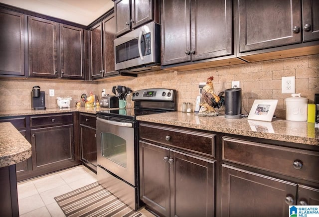 kitchen with appliances with stainless steel finishes, dark brown cabinetry, light tile patterned flooring, and backsplash