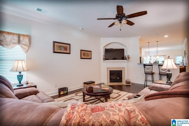 living room with hardwood / wood-style floors, crown molding, and ceiling fan