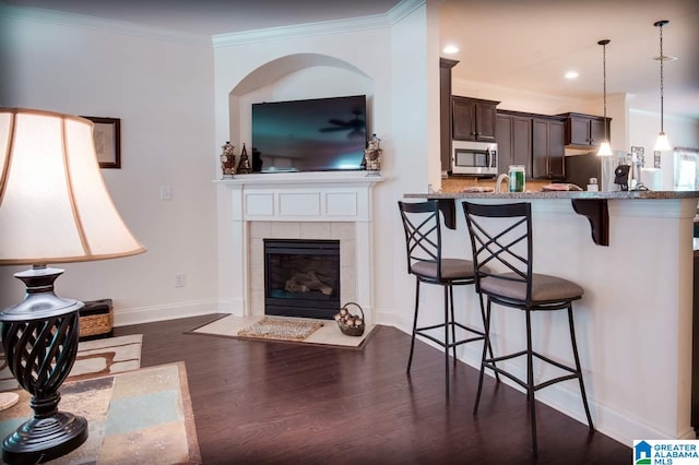 living room featuring crown molding, dark hardwood / wood-style flooring, and a fireplace