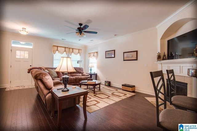 living room with a tiled fireplace, ornamental molding, dark hardwood / wood-style floors, and ceiling fan