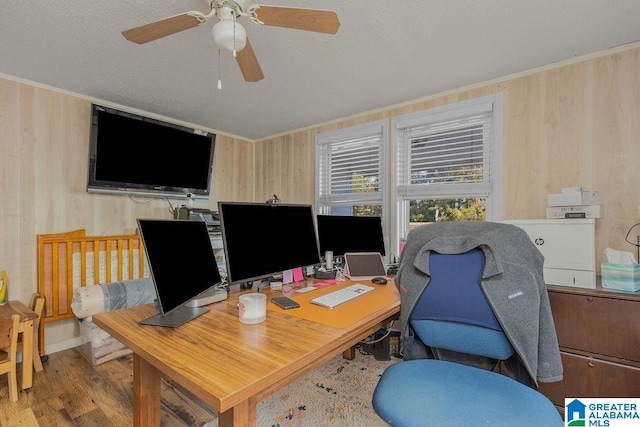 home office with ceiling fan, wood walls, and light hardwood / wood-style flooring