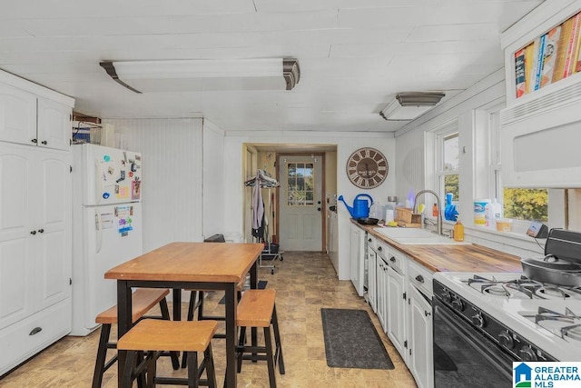 kitchen featuring wood walls, white cabinets, sink, and white appliances