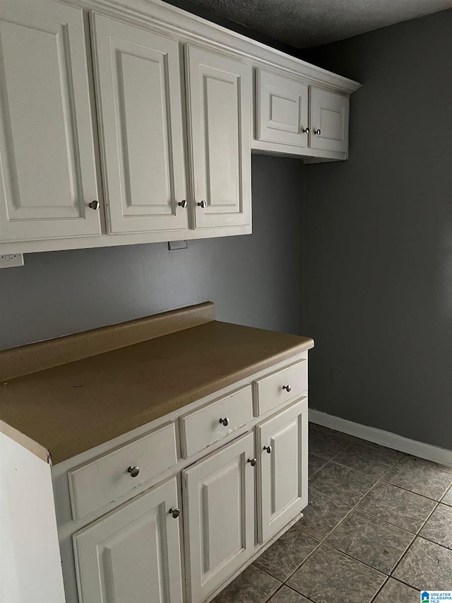 kitchen featuring white cabinets, a textured ceiling, and dark tile patterned floors