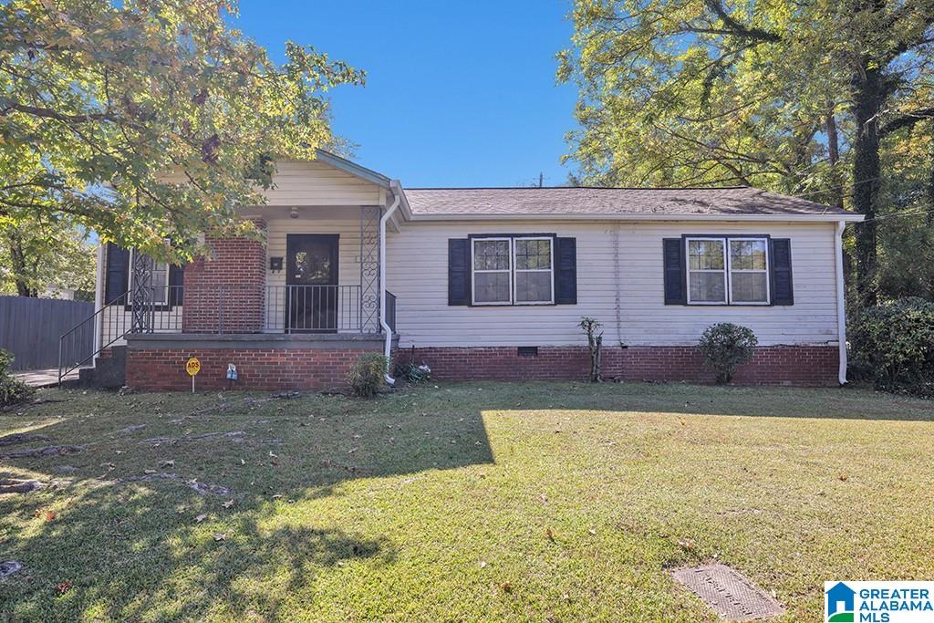 ranch-style house with a front yard and covered porch