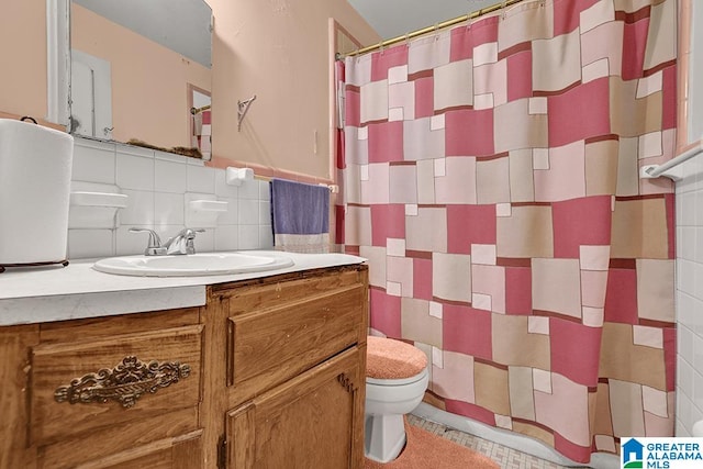 bathroom with tile walls, vanity, curtained shower, and toilet