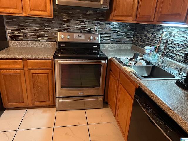 kitchen with light tile patterned floors, appliances with stainless steel finishes, sink, and decorative backsplash