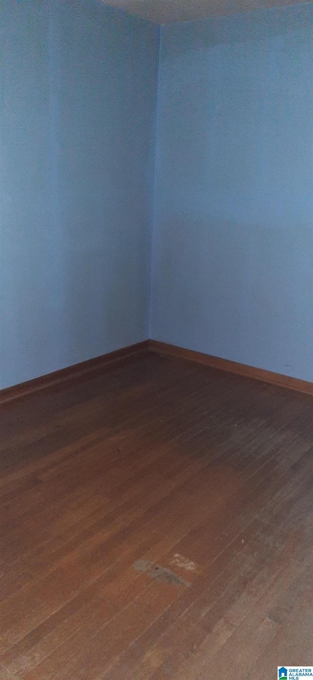 spare room featuring baseboards and wood finished floors