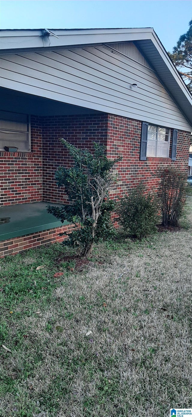 view of home's exterior with a lawn and brick siding