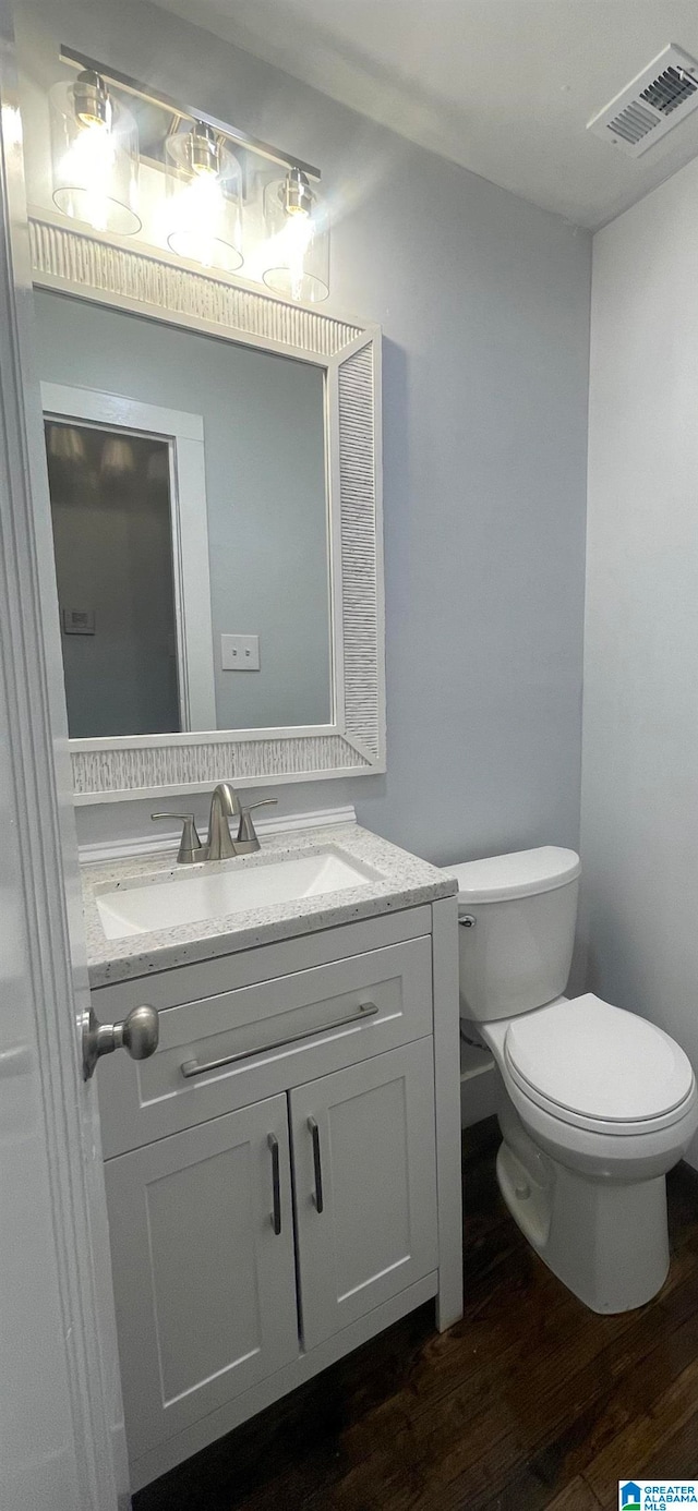 bathroom with wood-type flooring, vanity, and toilet