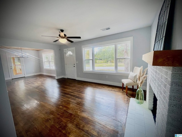 living room featuring ceiling fan with notable chandelier, dark hardwood / wood-style floors, and a fireplace