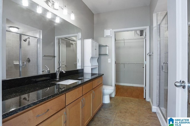 bathroom featuring vanity, a shower with shower door, toilet, and tile patterned floors