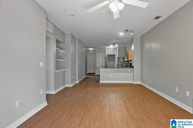 unfurnished living room featuring light hardwood / wood-style flooring, sink, and ceiling fan