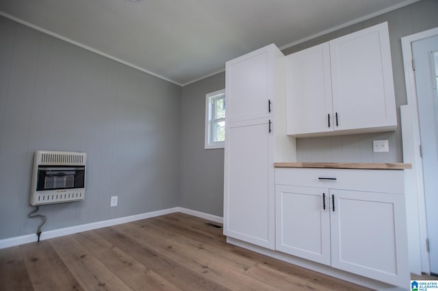 interior space featuring light hardwood / wood-style floors, ornamental molding, and heating unit