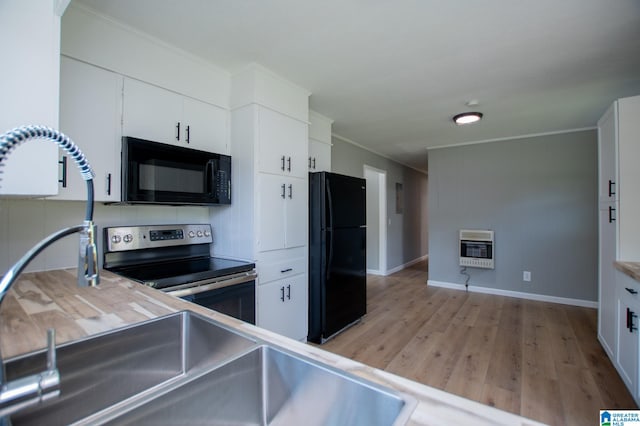 kitchen with black appliances, white cabinetry, heating unit, ornamental molding, and light hardwood / wood-style flooring