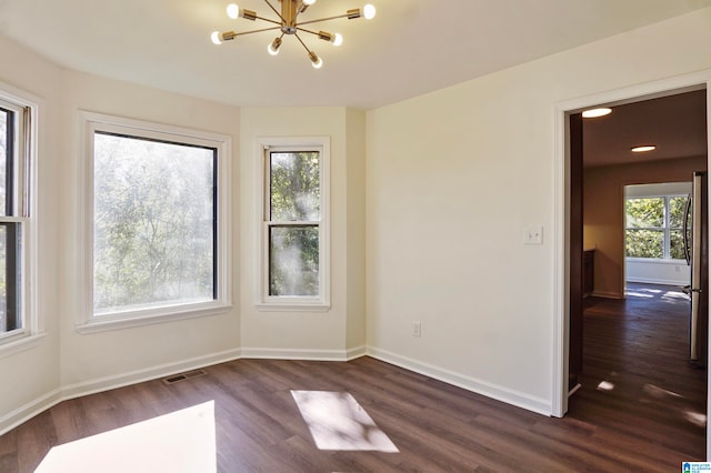 empty room featuring a notable chandelier and dark hardwood / wood-style flooring