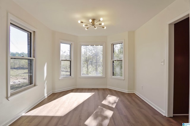 unfurnished dining area featuring dark hardwood / wood-style flooring and an inviting chandelier