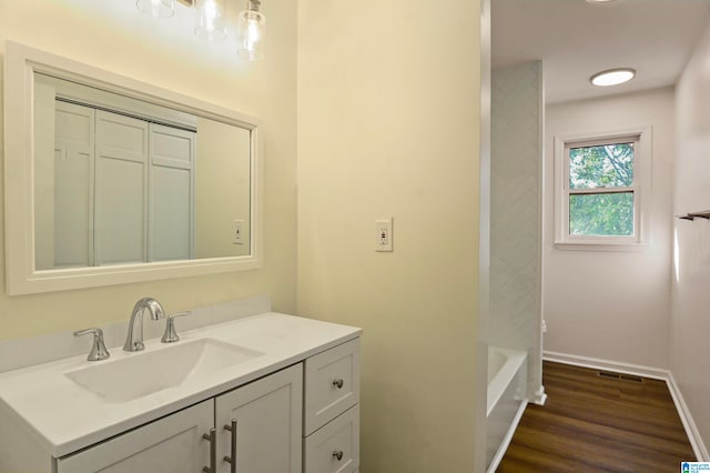 bathroom with vanity, a tub, and wood-type flooring