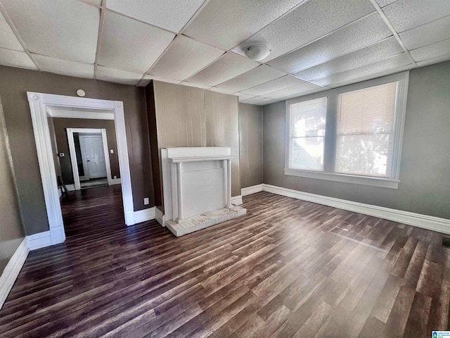 unfurnished living room featuring a drop ceiling and dark hardwood / wood-style floors