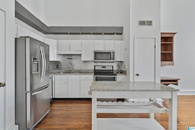 kitchen featuring stainless steel appliances, white cabinetry, backsplash, sink, and dark wood-type flooring