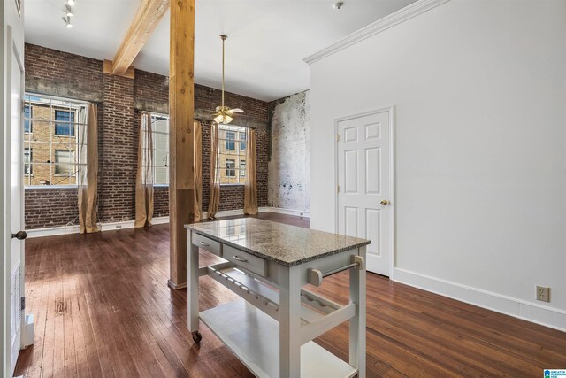 kitchen with stone countertops, brick wall, ornamental molding, ceiling fan, and dark hardwood / wood-style flooring