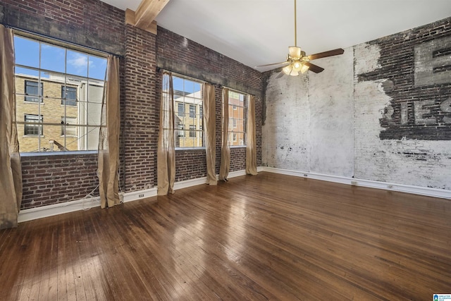 empty room with a wealth of natural light, ceiling fan, hardwood / wood-style floors, and beamed ceiling